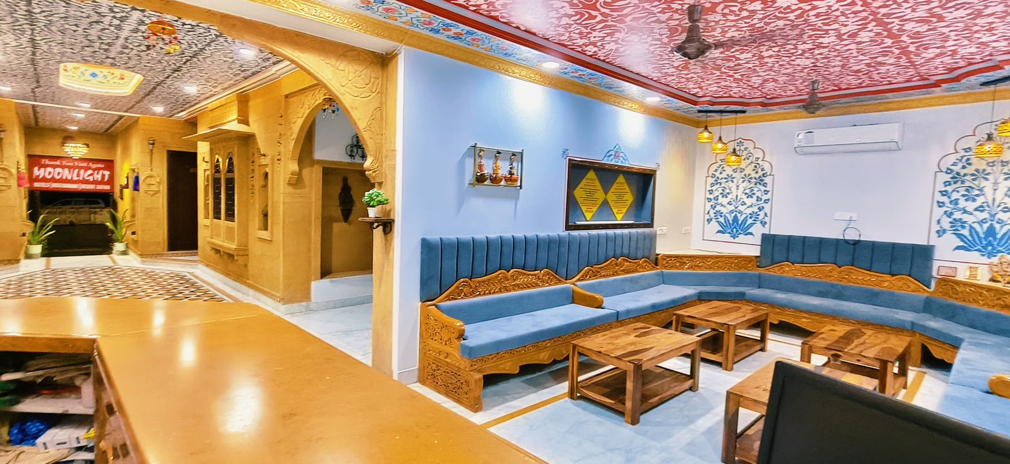 Lobby of Hotel Moonlight with a carved sandstone arch beside blue seating