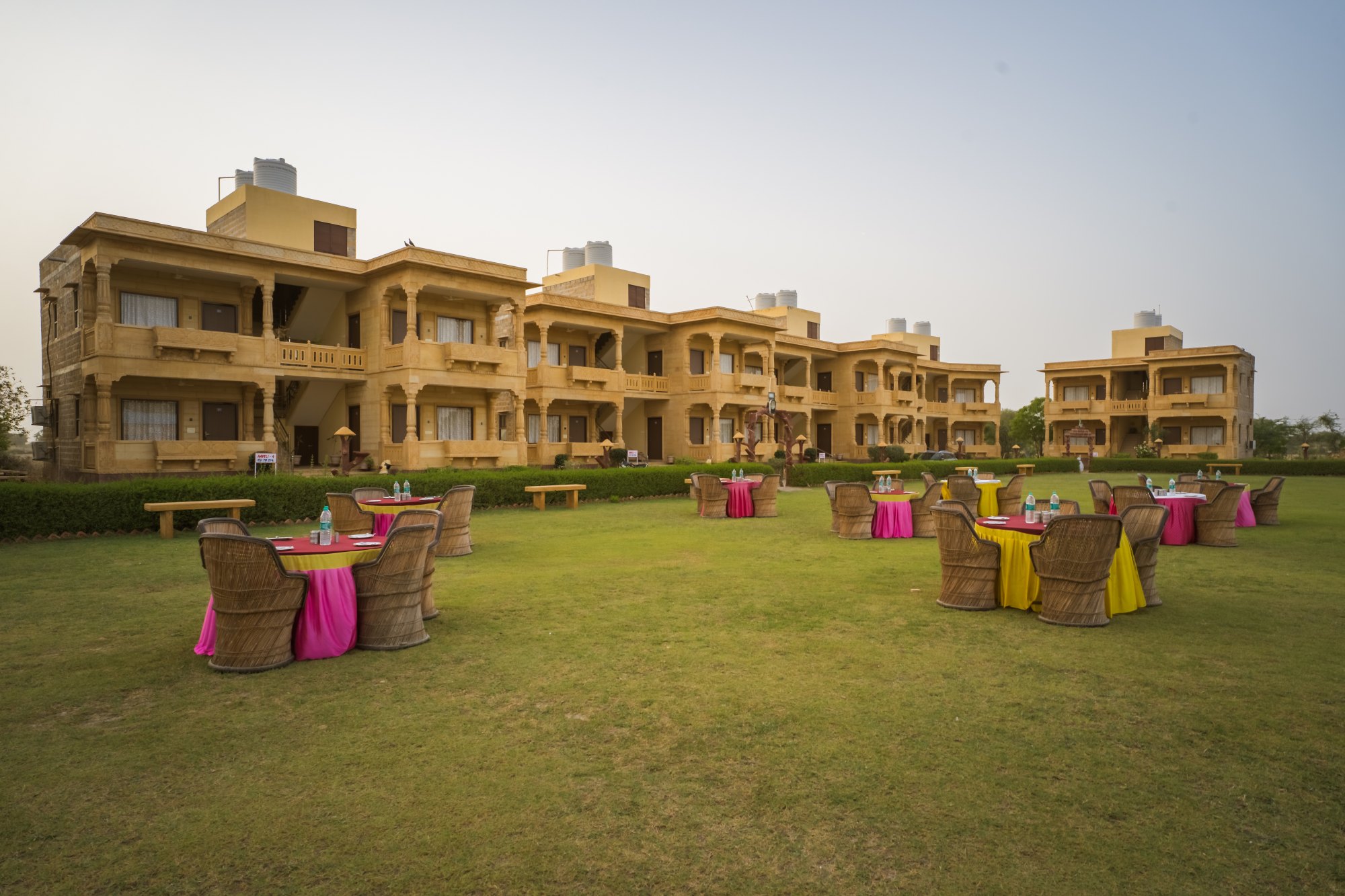 Sandstone haveli-style buildings and lawn at Moonlight Nature Resort